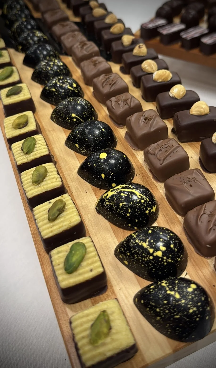Mignardises assortment — pistachio sablés, hazelnut pralinés and gold-flecked dark chocolate domes
